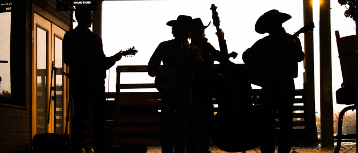 Silhouettes of people playing instruments against a sunset sky.